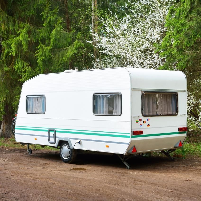 A White Trailer With Green Stripes Is Parked In A Dirt Lot — Kingston Caravan Repairs In Heatherbrae, NSW
