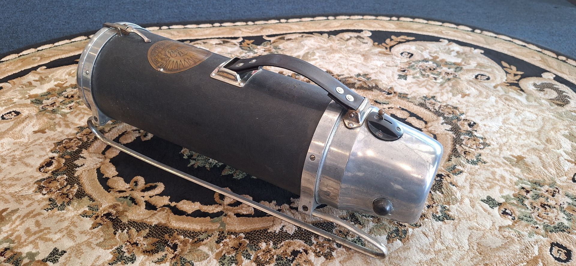 Black and silver metal tank or canister lying on a patterned rug