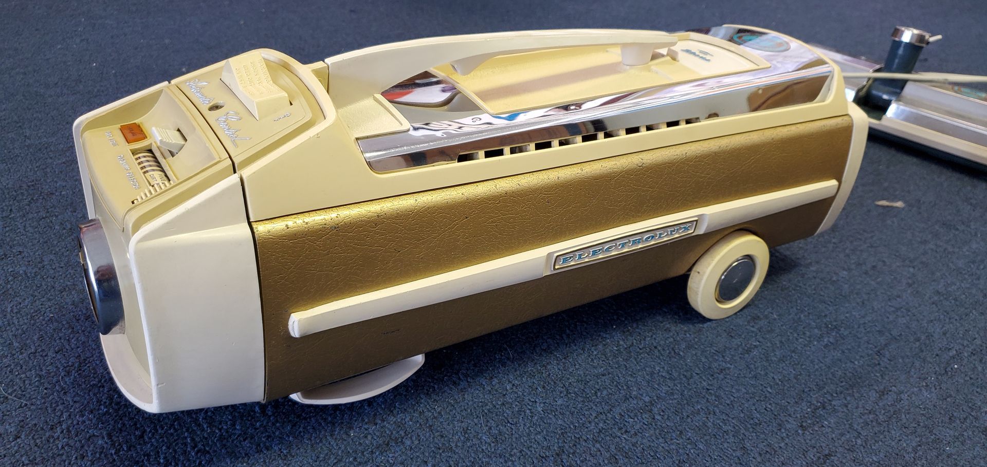 Vintage beige and gold boombox with handle and cassette deck on a carpeted floor