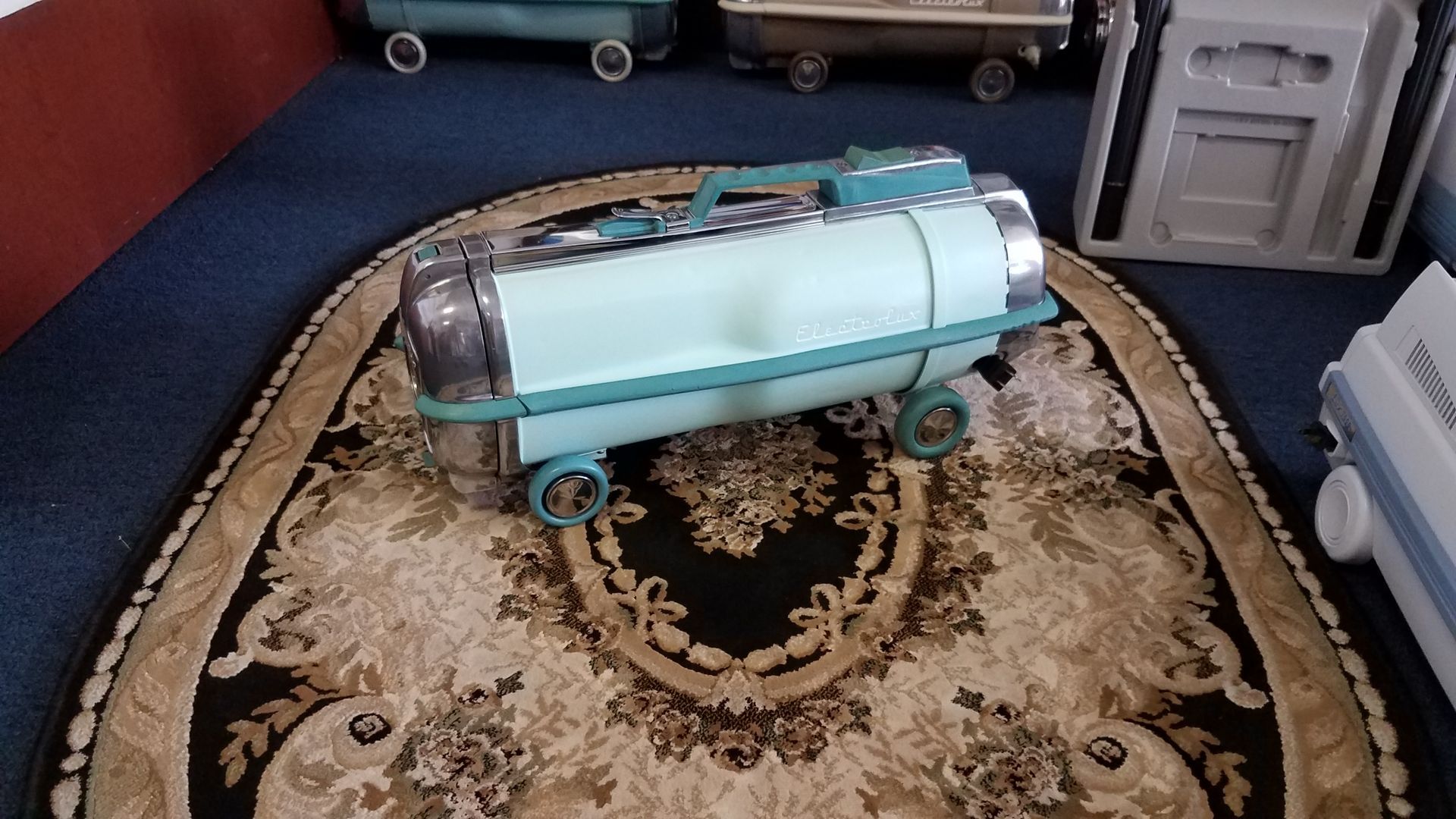 A light blue baby bassinet on a patterned rug in a room