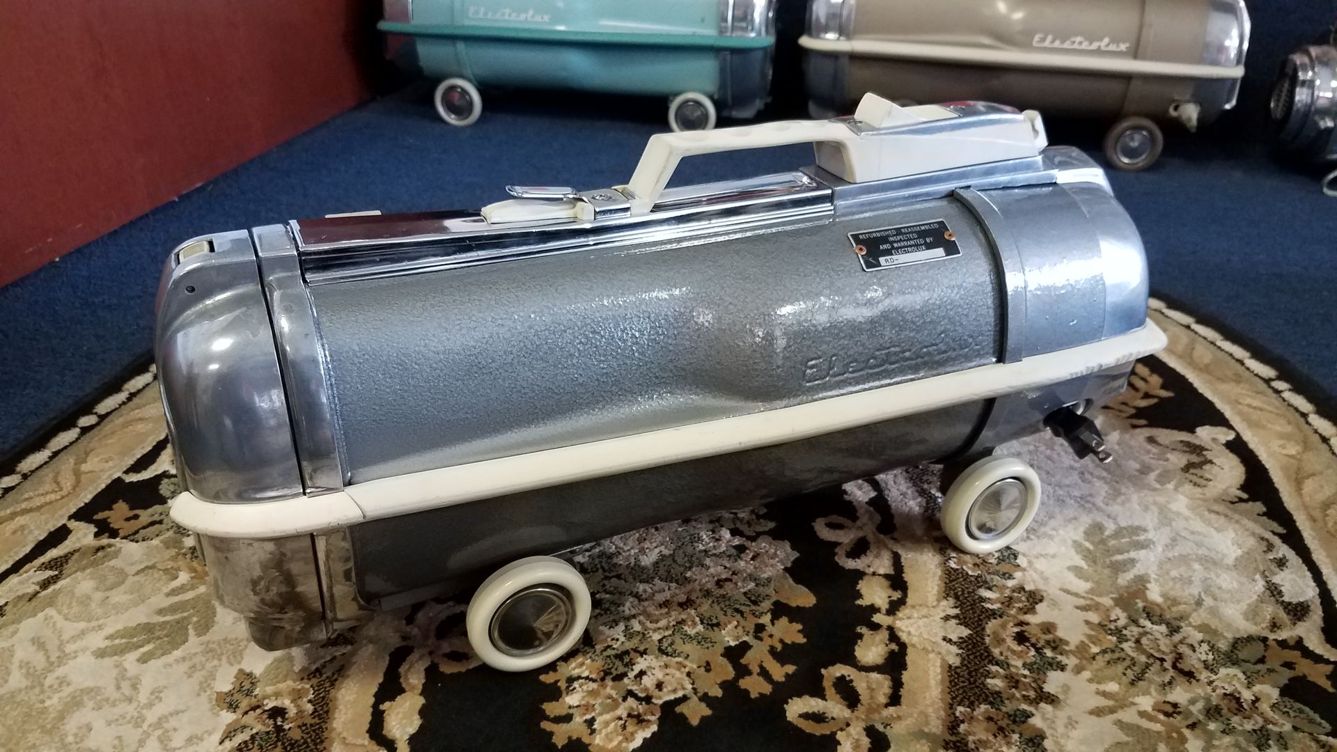 Blue vintage toy tanker truck on a patterned rug, with white wheels and silver details