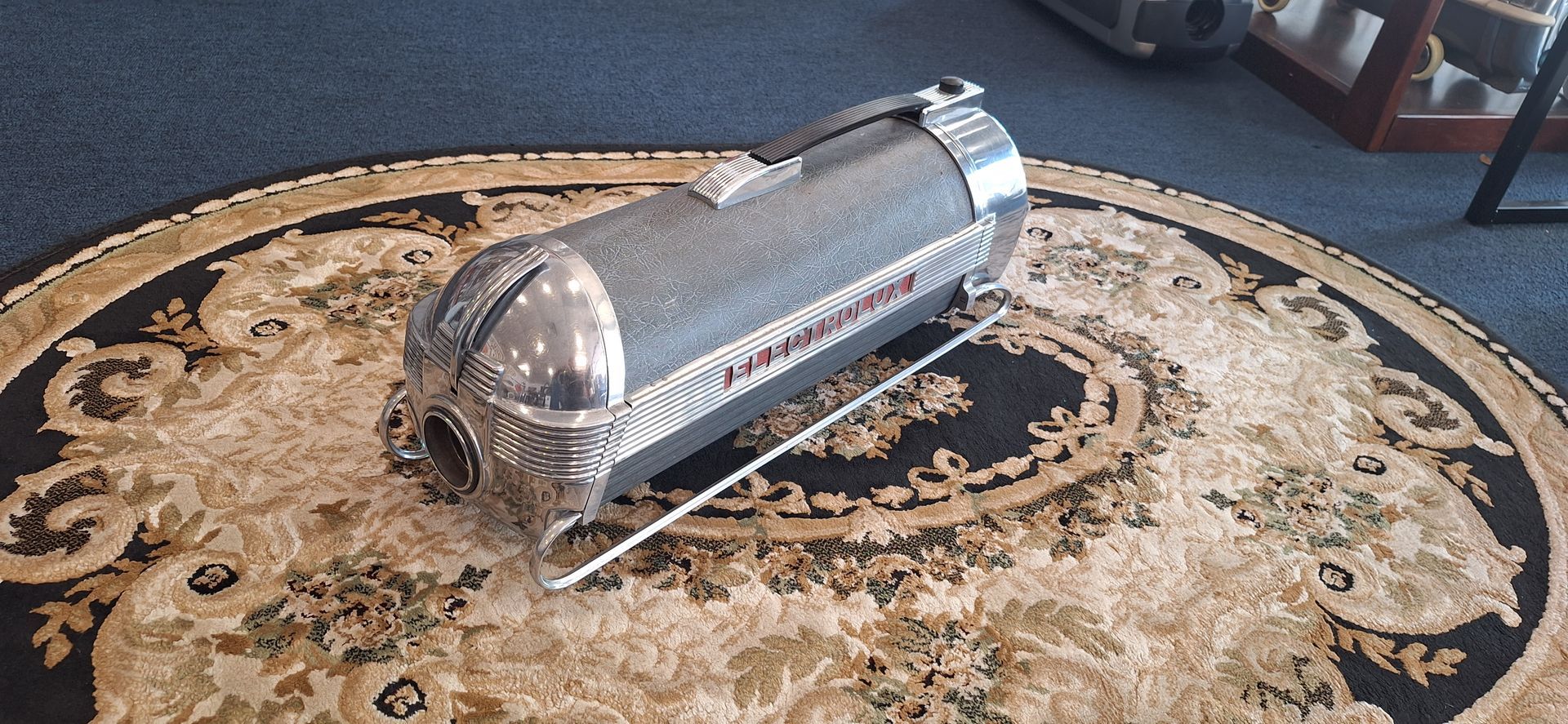 Chrome capsule on a patterned round rug in a room