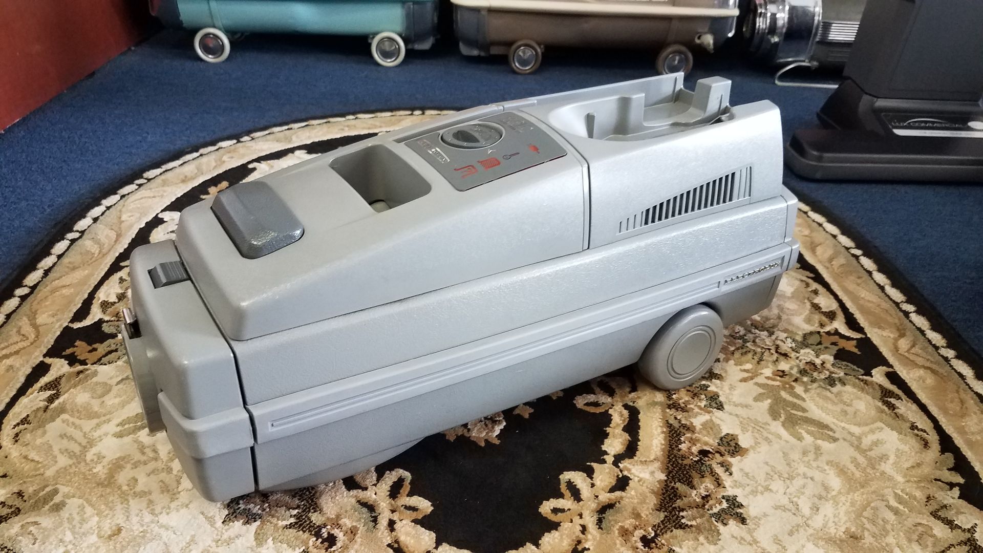 Gray futuristic toy vehicle with tinted windows and wheel-like sides on a patterned rug