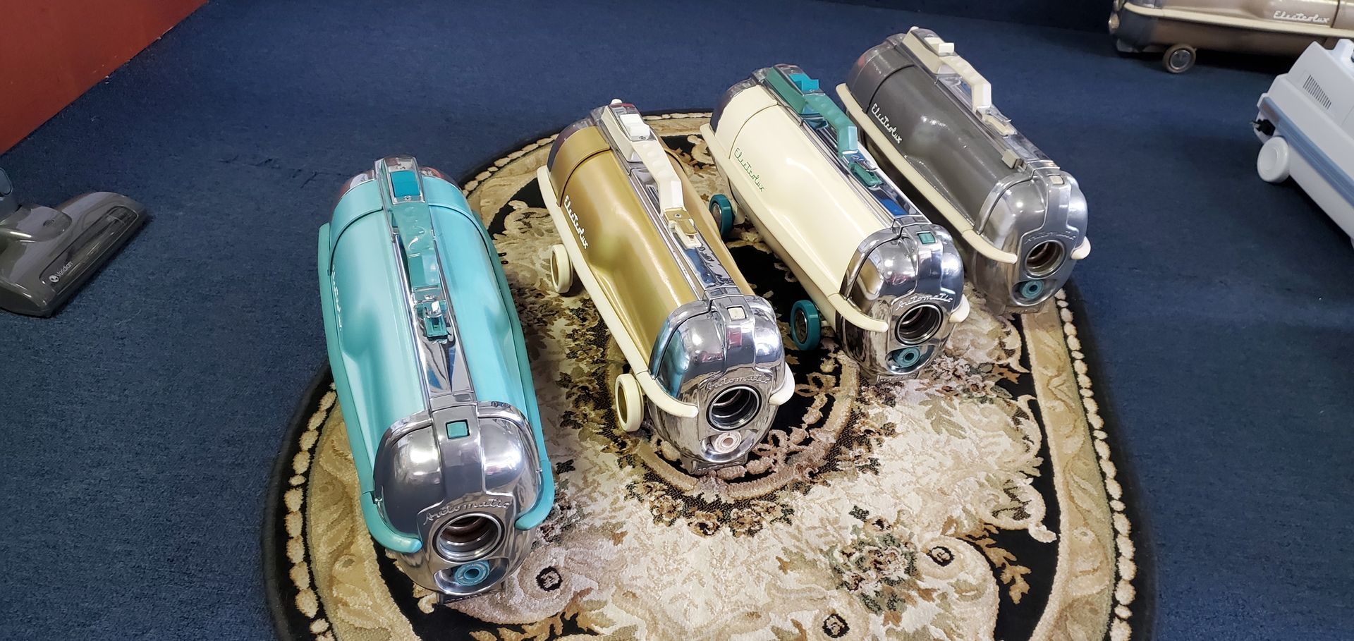 Four vintage cars in turquoise, gold, cream, and silver on a round display base