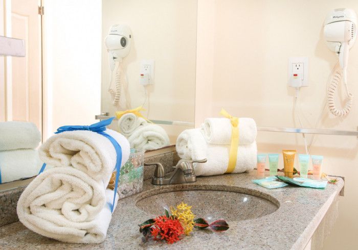 Hotel bathroom vanity with rolled towels, toiletries, and a large mirror