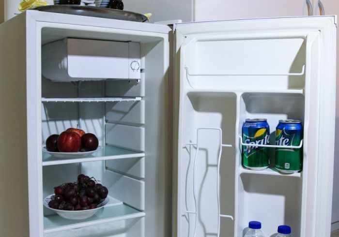 Open refrigerator with shelves of fruit and door compartments holding drinks and snacks