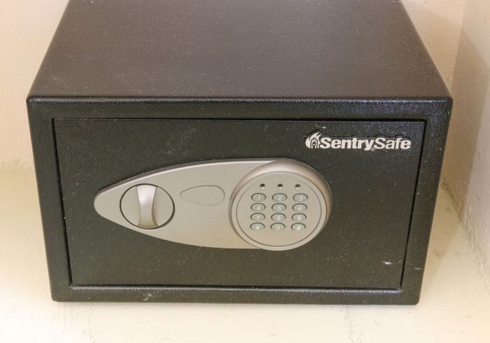 Black SentrySafe lockbox with silver keypad and handle on a shelf.