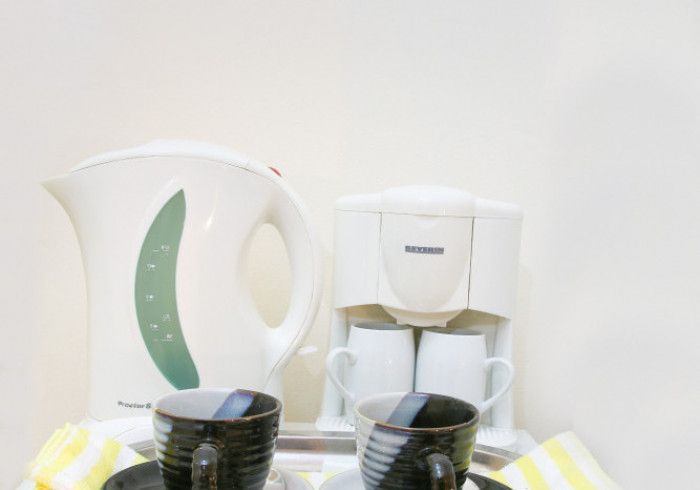 White electric kettle and coffee maker with two cups on a striped counter