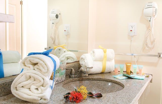 Bathroom vanity with folded towels, toiletries, and wall-mounted hair dryers