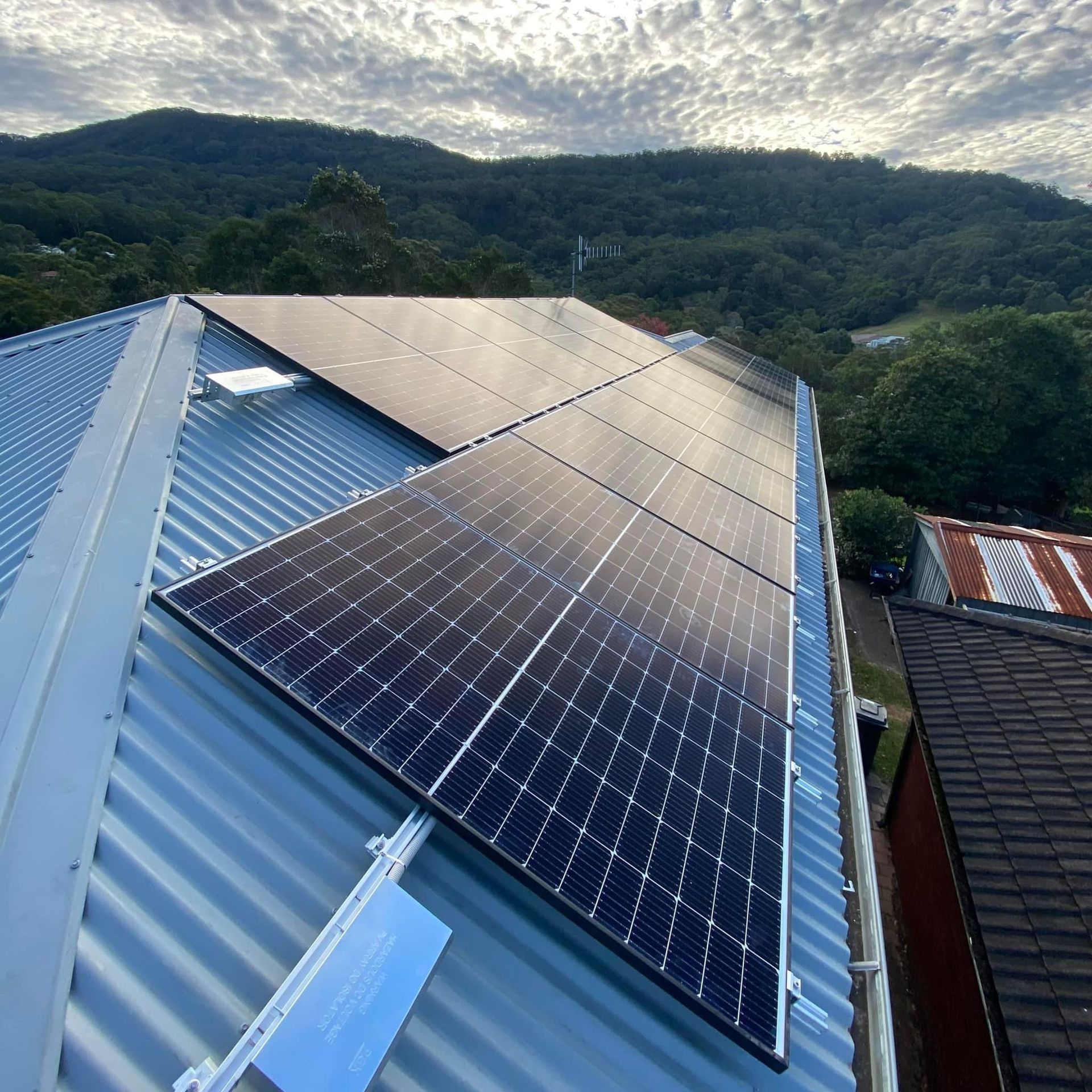 A Large Amount Of Solar Panels Are Sitting On Top Of A Roof — AH Electrical in West Ballina, NSW