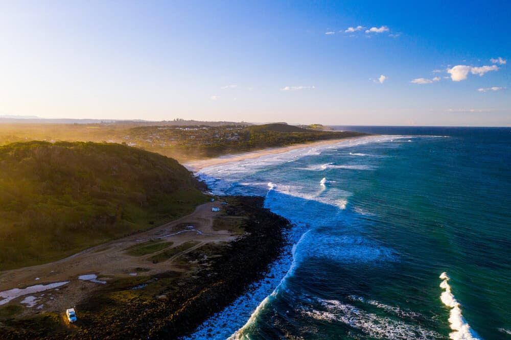 An Aerial View of a Beach and Ocean at Sunset — AH Electrical in Ballina, NSW