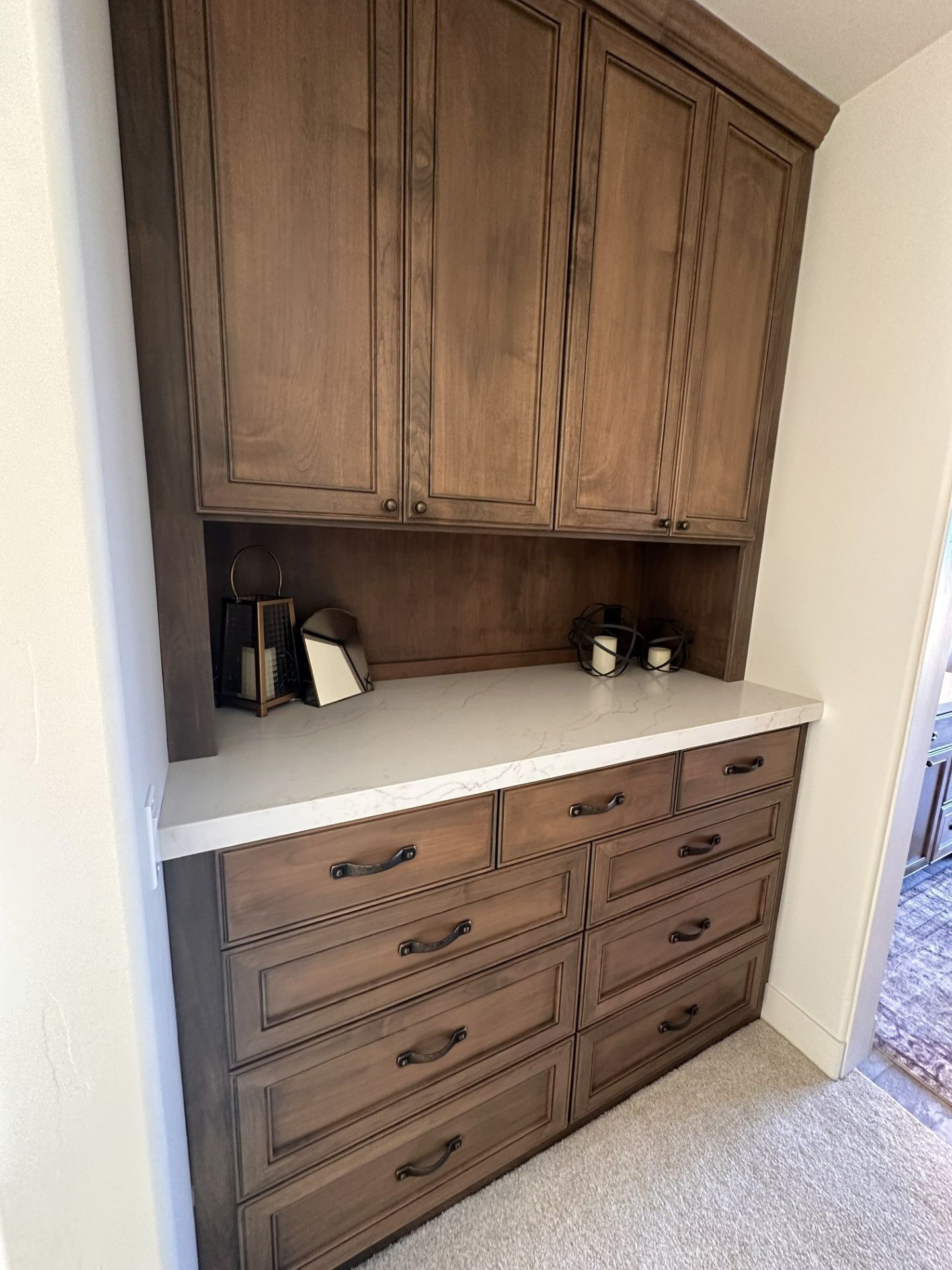 Built-in wooden cabinetry with a white countertop and decorative drawer detailing in a residential home setting.