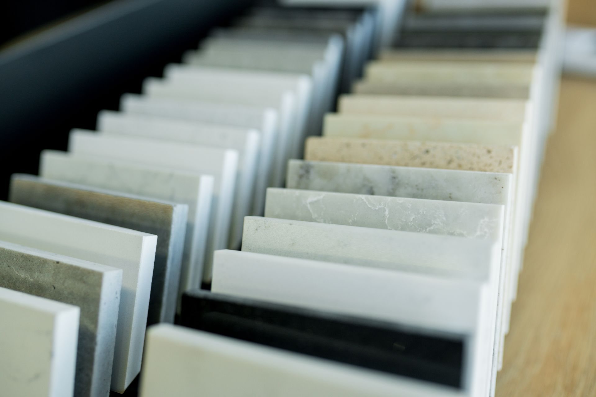 An angled close-up of a sample rack featuring various stone, quartz, and laminate countertop material swatches. An angled close-up of a sample rack featuring various stone, quartz, and laminate countertop material swatches.