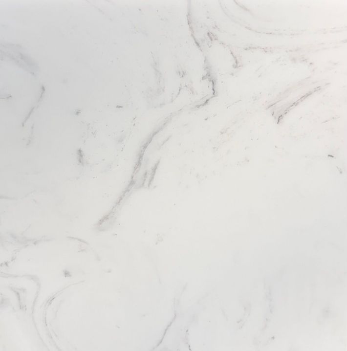 A close-up view of white marble stone with faint, soft grey veining throughout the smooth, polished surface. A close-up view of white marble stone with faint, soft grey veining throughout the smooth, polished surface.