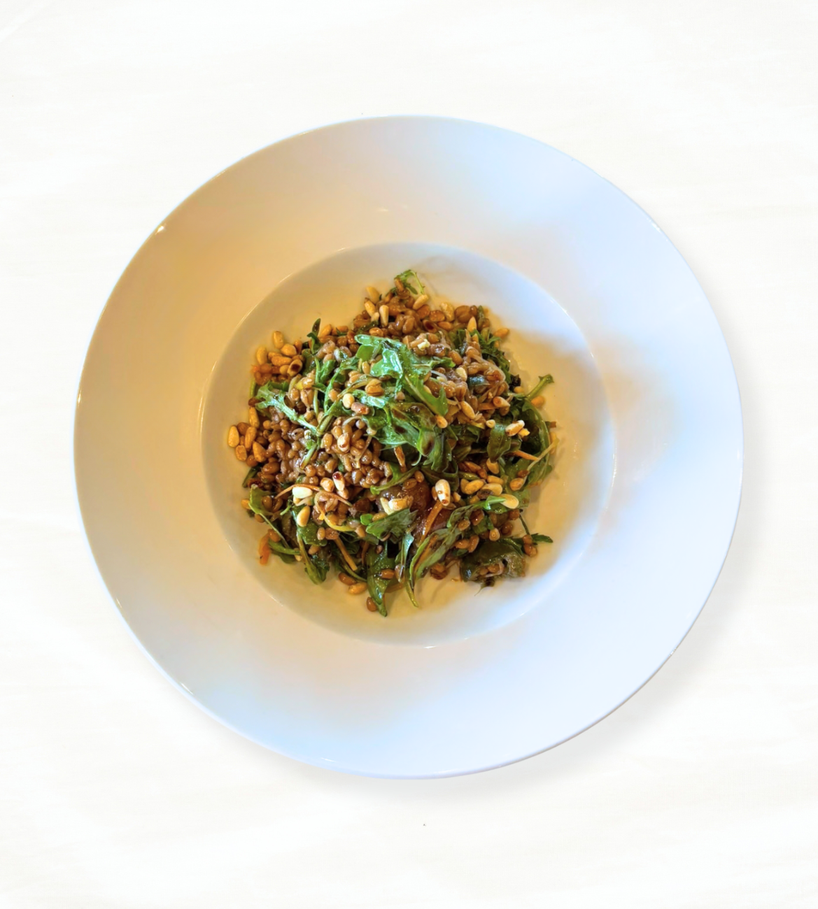 A white plate of Farro Grain on a white tablecloth-covered table. 