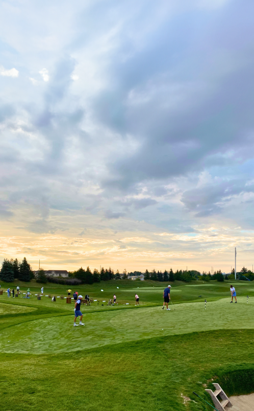 The driving range at Eagles Nest Golf Club with a cloudy blue sky.