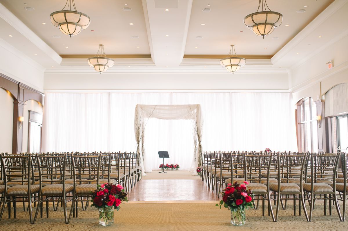 Indoor wedding ceremony in the Great Hall. Simple black chairs are facing a large curtain linen covered window.
