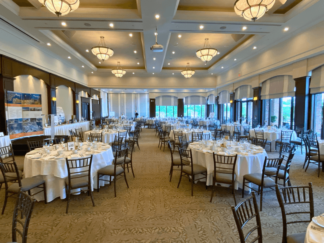 The Great Hall at Eagles Nest Golf Club with tables and chairs for a golf tournament.