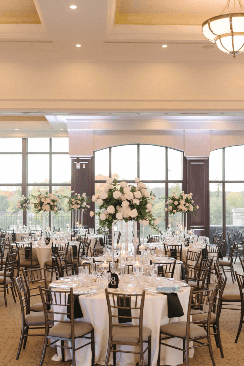 Tables set up with tall white floral centerpieces for a wedding in the Great Hall.