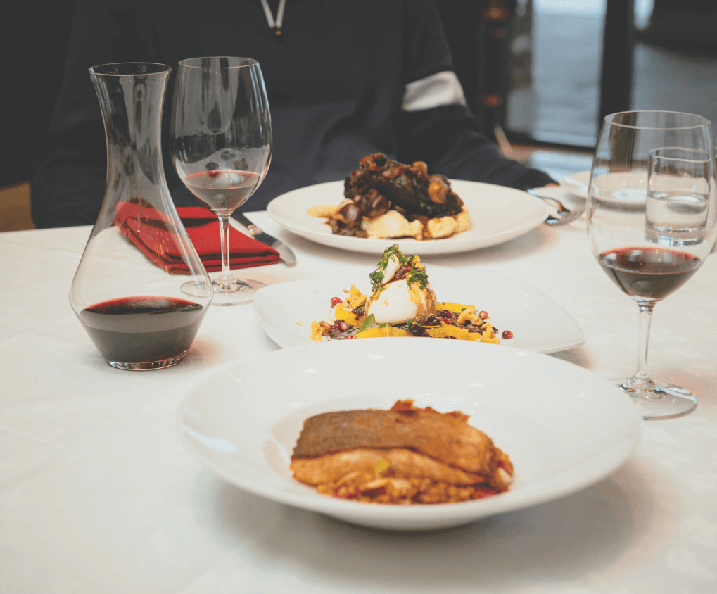 One plate of salmon and one plate of lamb, paired with two glasses of white wine.