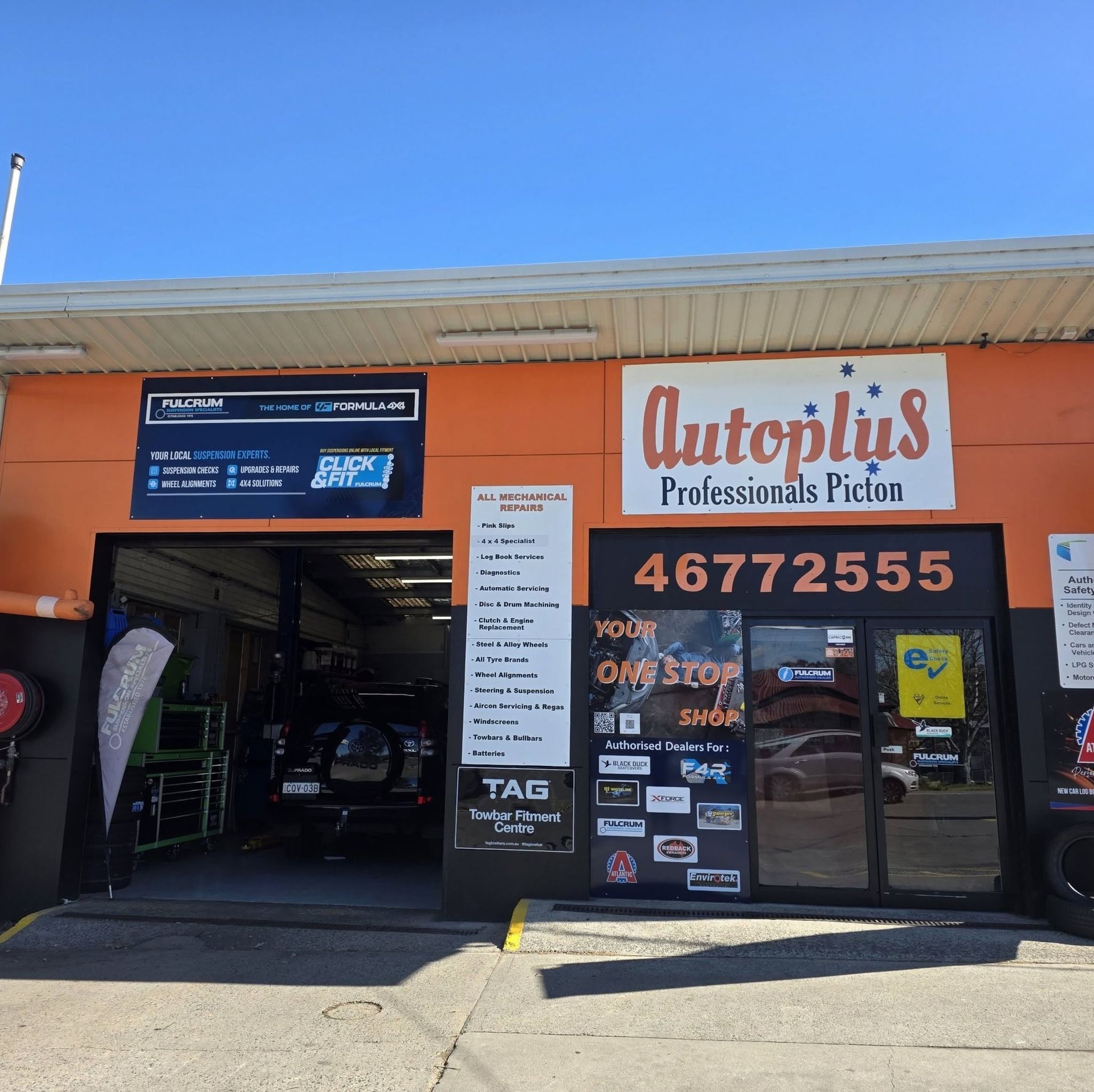 Autoplus Pésimas y Pico auto shop with open garage and orange storefront under a blue sky — Autoplus Professionals Picton in Picton, NSW