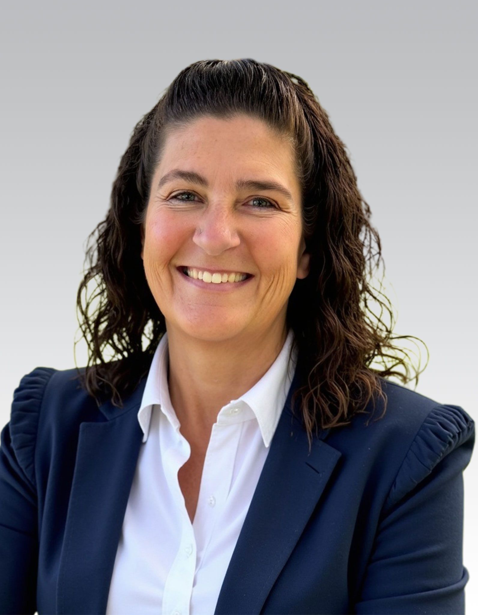 Smiling woman in a navy blazer and white shirt against a light gray background