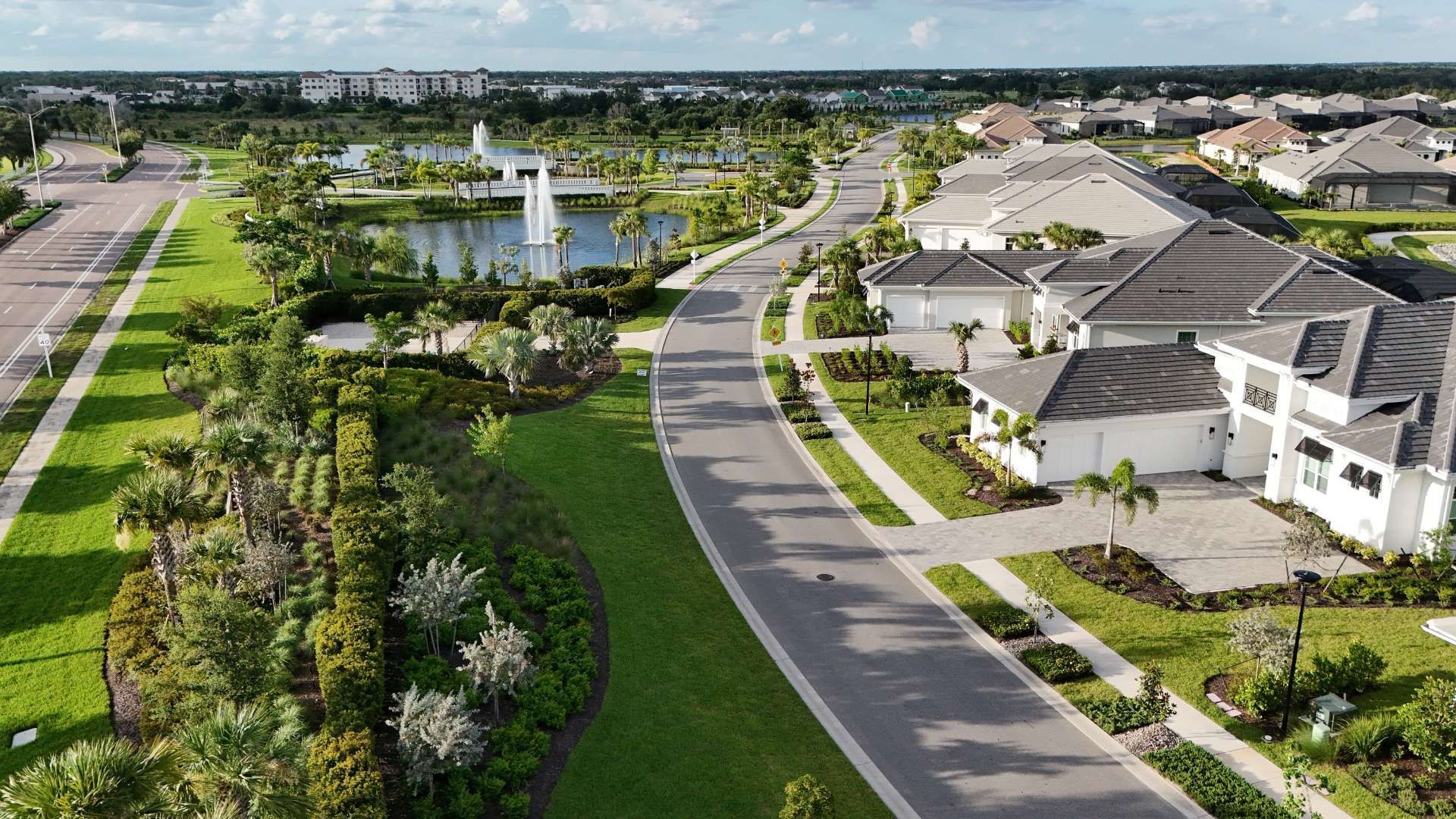 Aerial view of a landscaped suburban neighborhood with curving roads, houses, and a pond