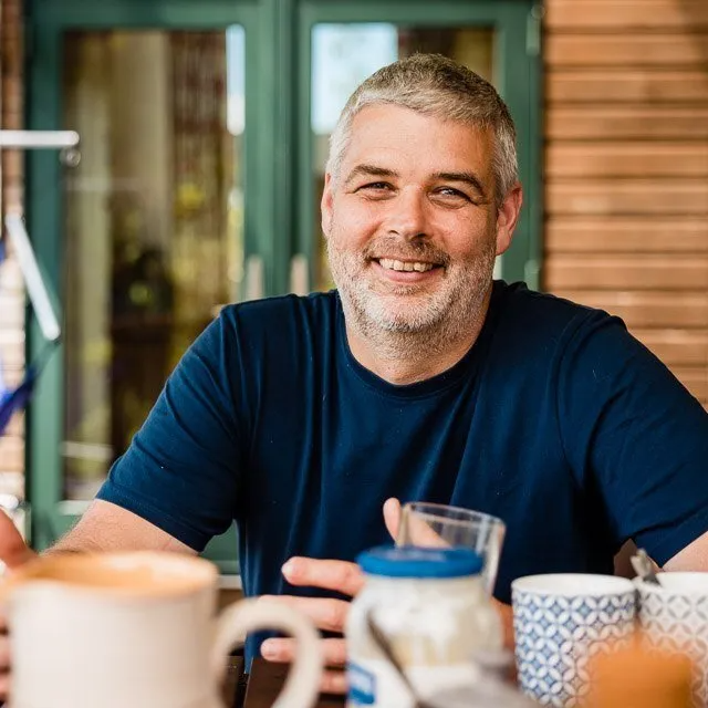 a man is sitting at a table with a cup of coffee .