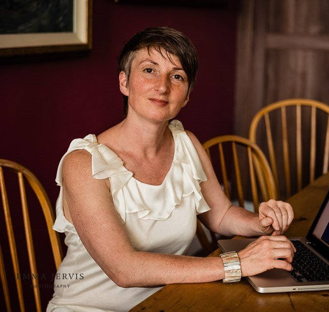 a woman in a white dress is sitting at a table with a laptop