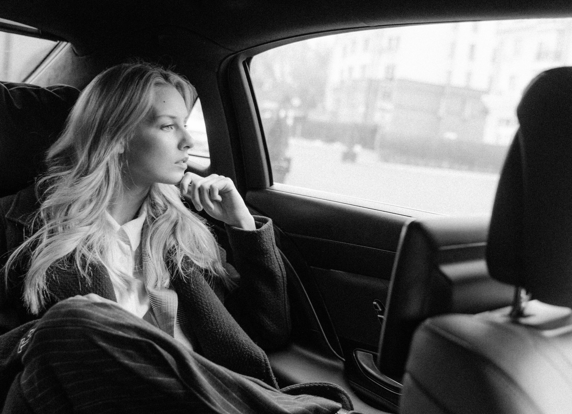 a woman is sitting in the back seat of a car looking out the window .