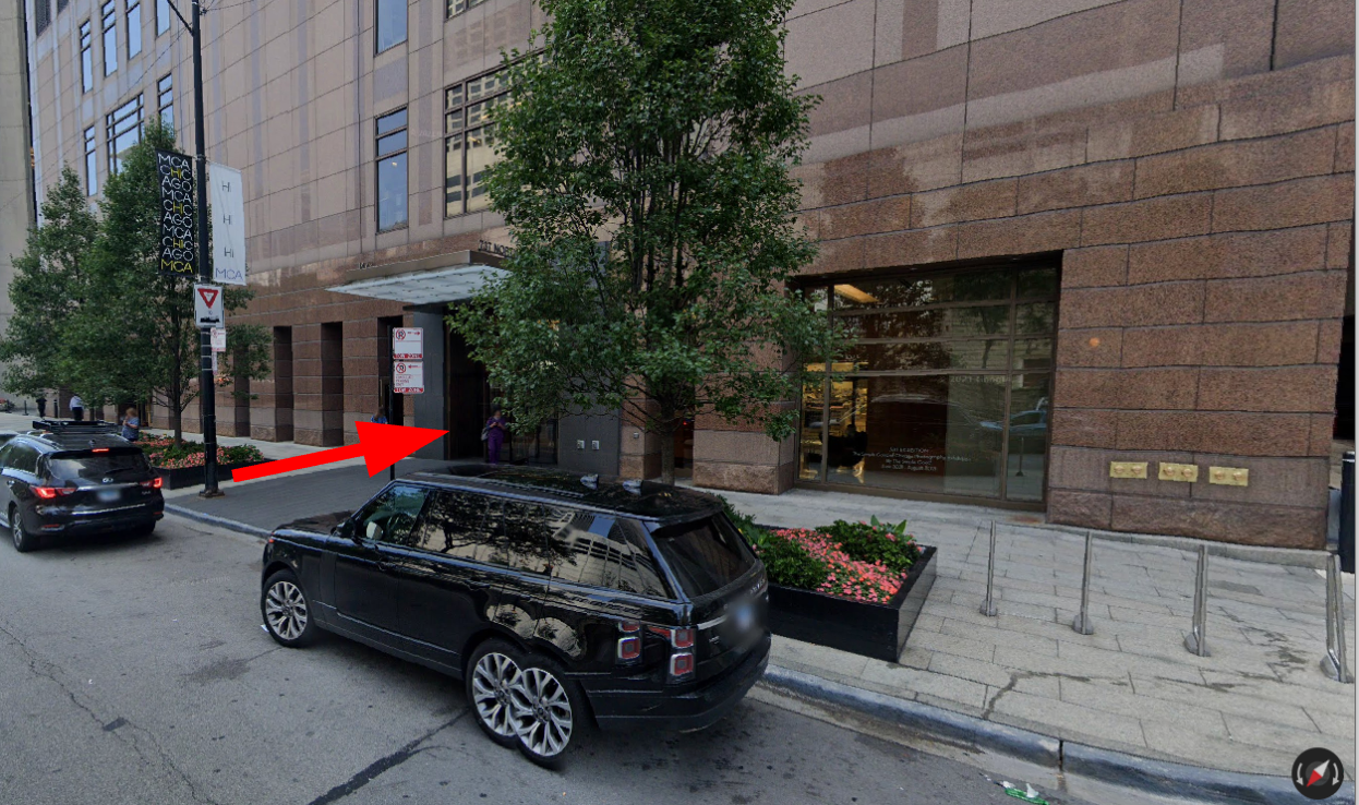 A black suv is parked on the side of the road in front of a building.
