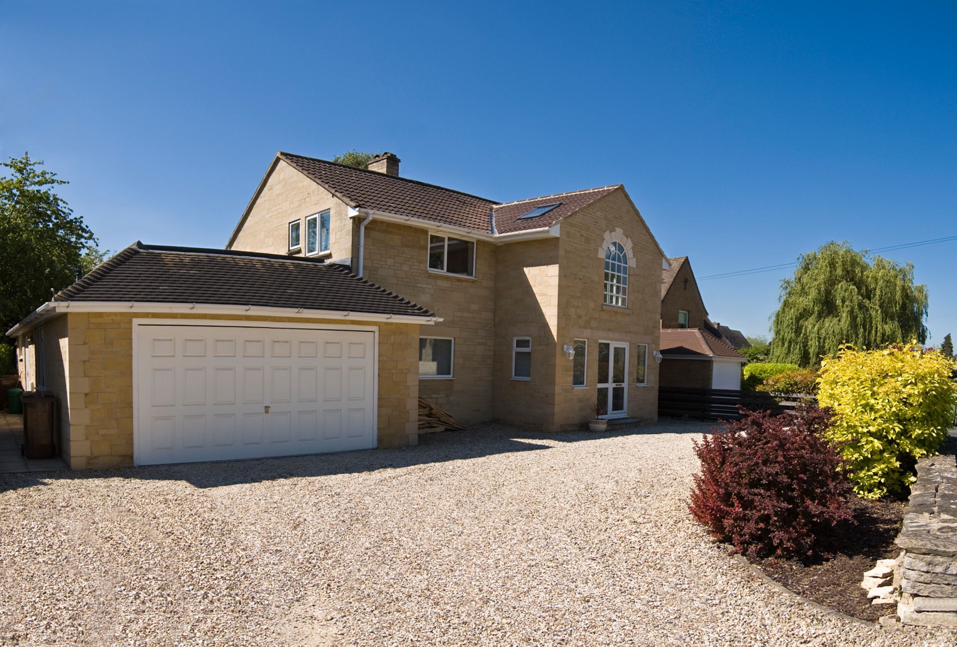 New build home in the picturesque Cotswolds, gravel drive and clear blue sky on a perfect summers day.