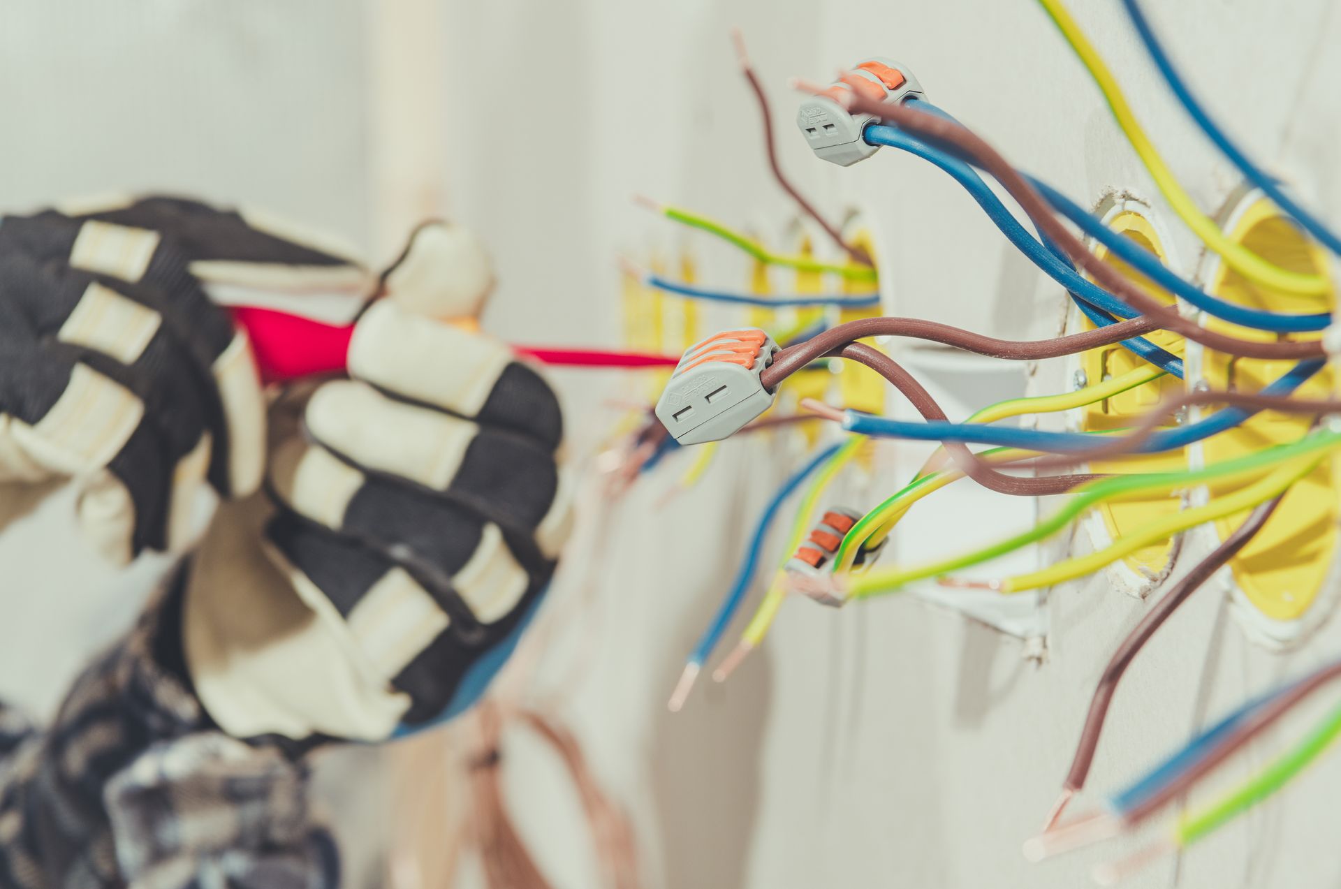 Exposed multicolored electrical wires beside a black-and-white braided cable in a wall opening.