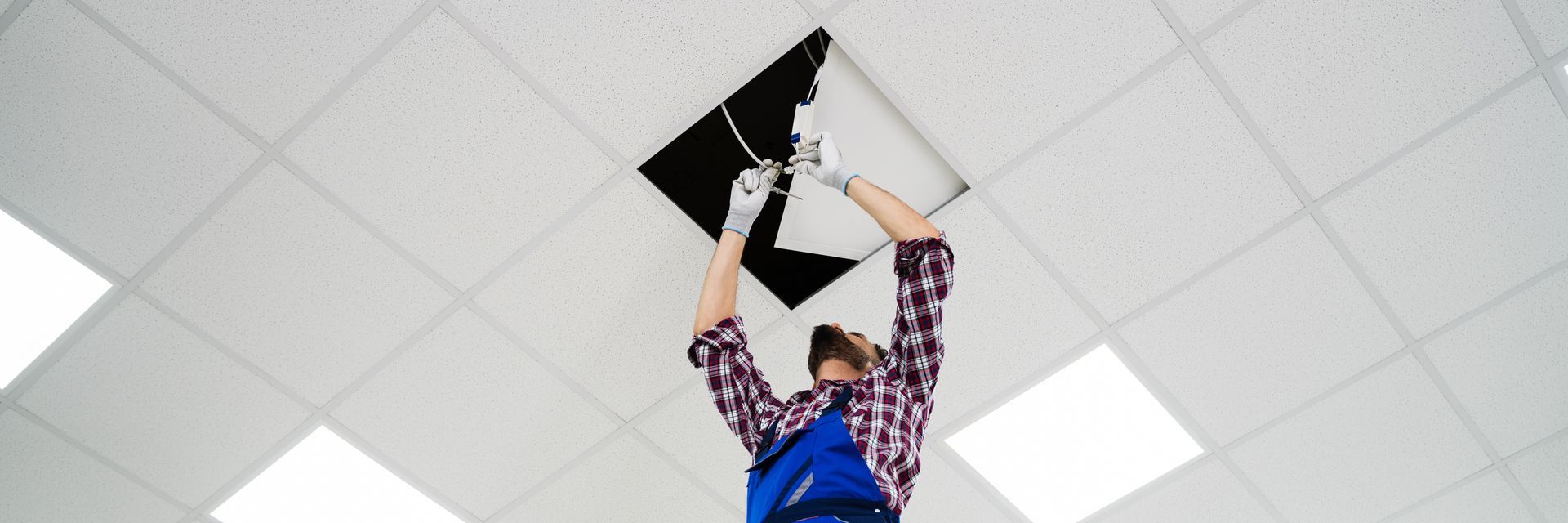 Person holding up a black-and-white triangular sign in a bright indoor room with ceiling lights.