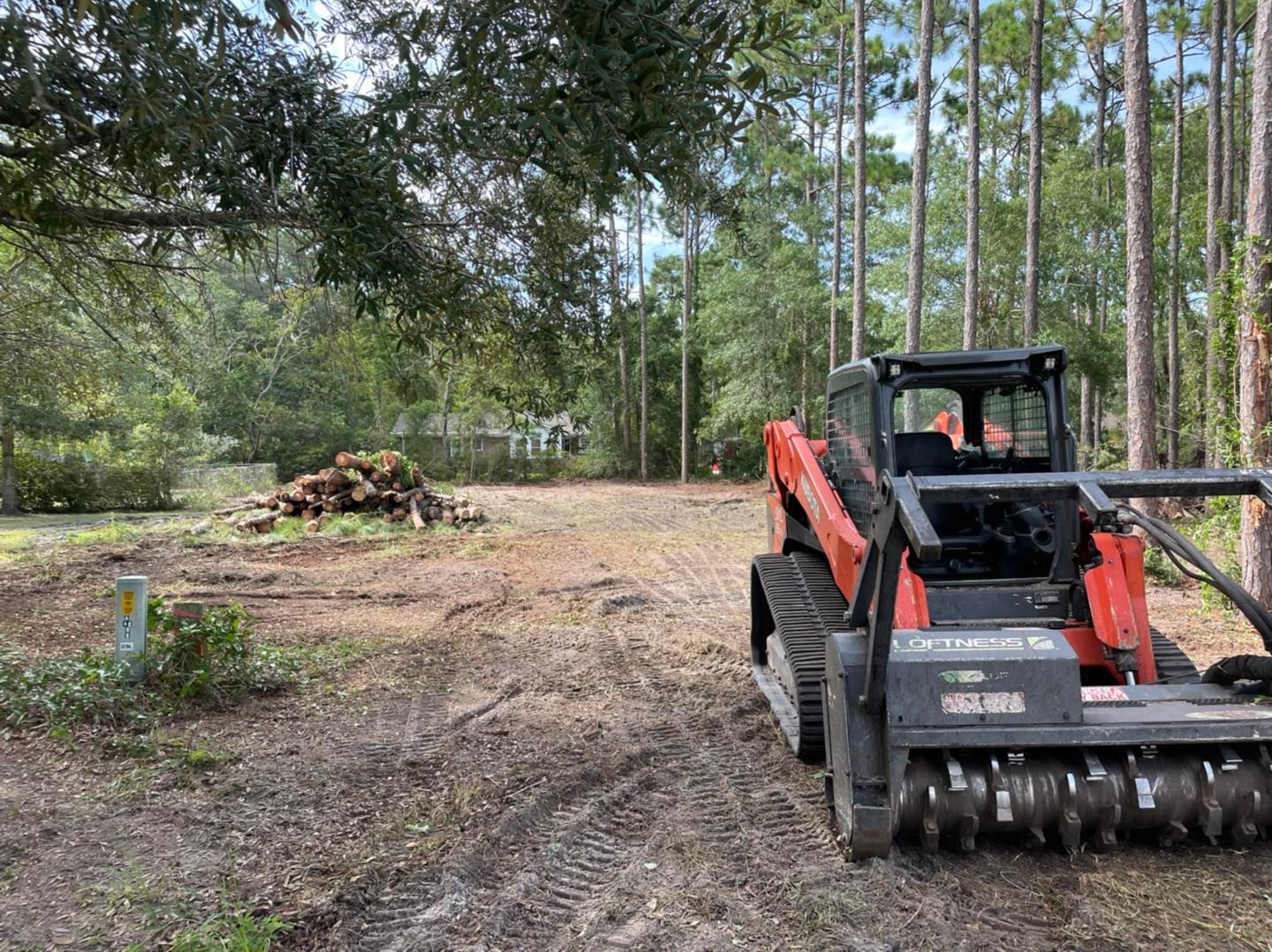 A bulldozer is sitting in the middle of a dirt road in the woods.