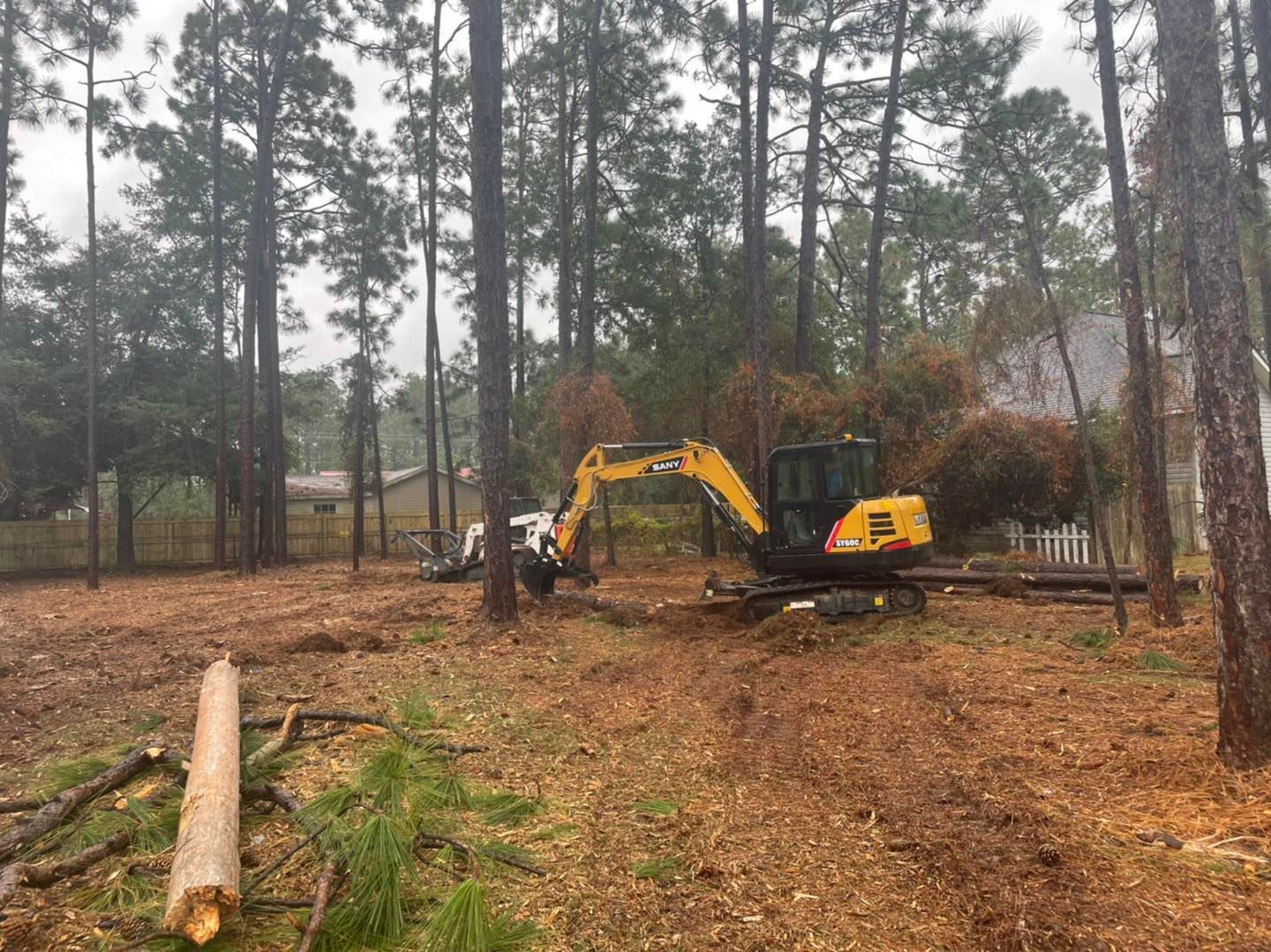 A yellow excavator is sitting in the middle of a forest.