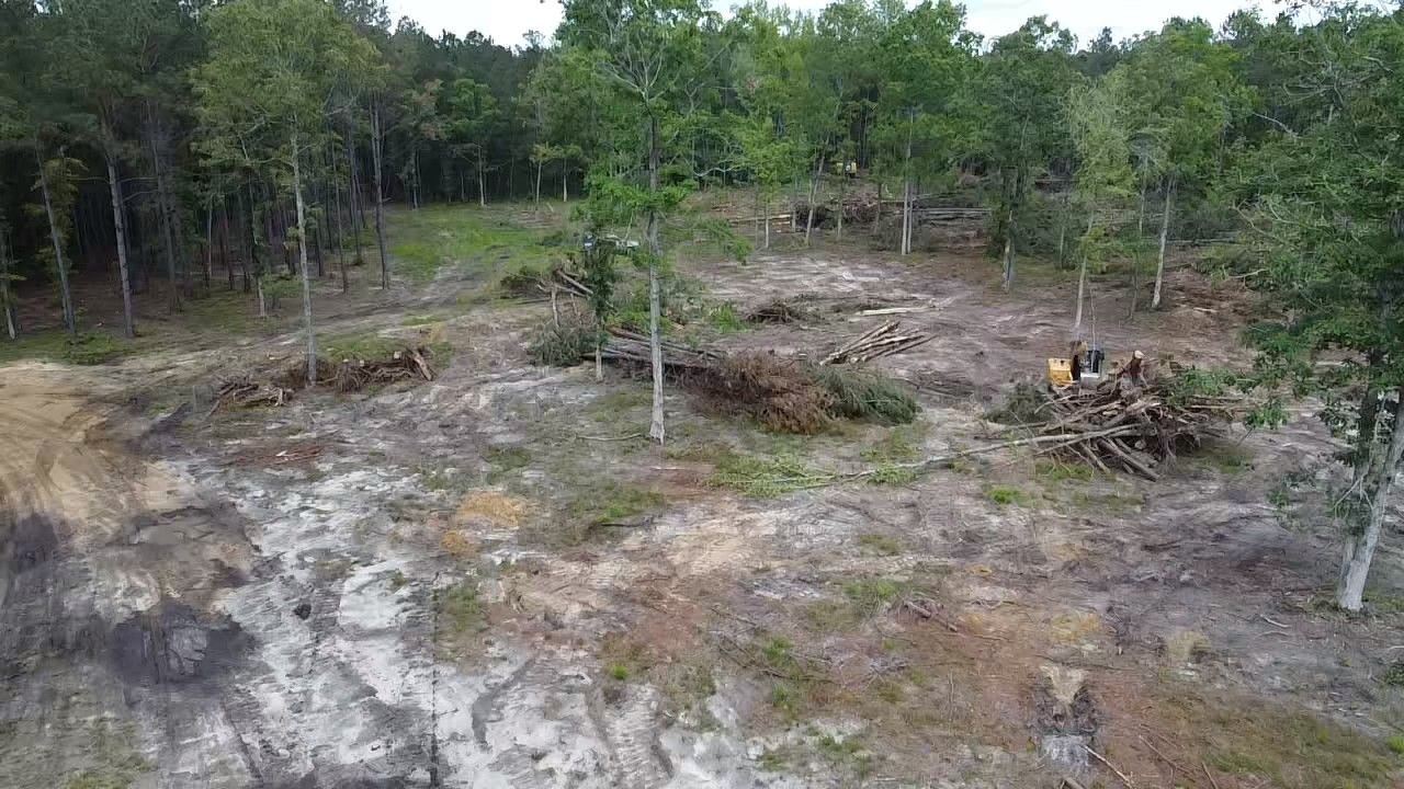 An aerial view of a muddy field with trees in the background.