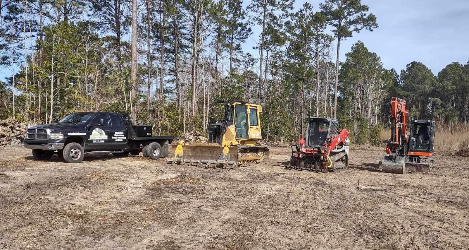A truck is towing a bulldozer and other construction vehicles in a field.