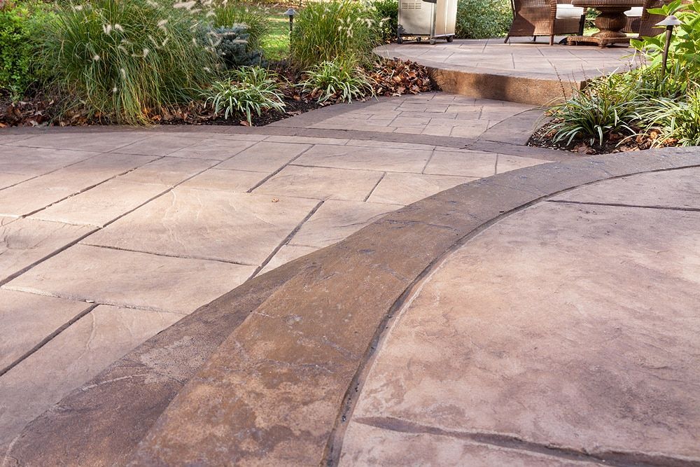 Stone walkway with a curved textured strip leading through a landscaped garden patio area