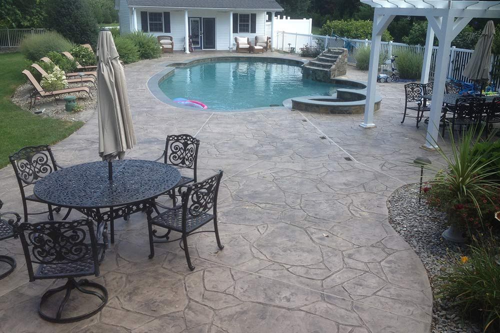 Backyard patio with round table, chairs, umbrella, and a swimming pool by a house