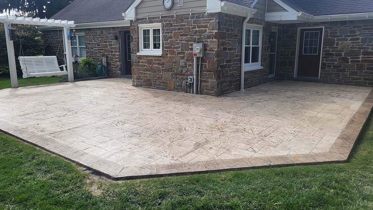 Backyard patio with stone paving, brick house walls, and a grassy lawn edge