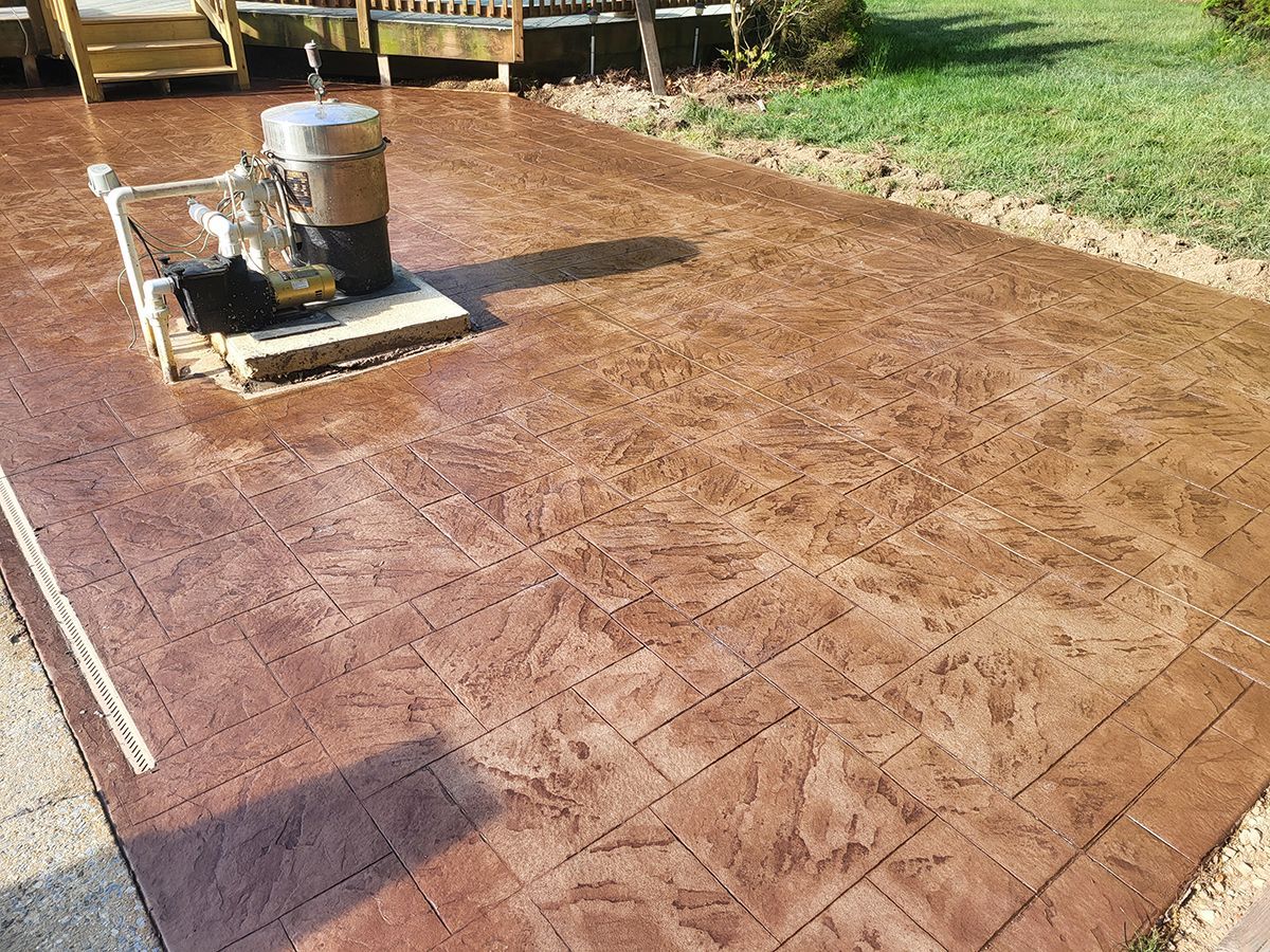 Freshly stamped concrete patio being finished with a roller tool outdoors