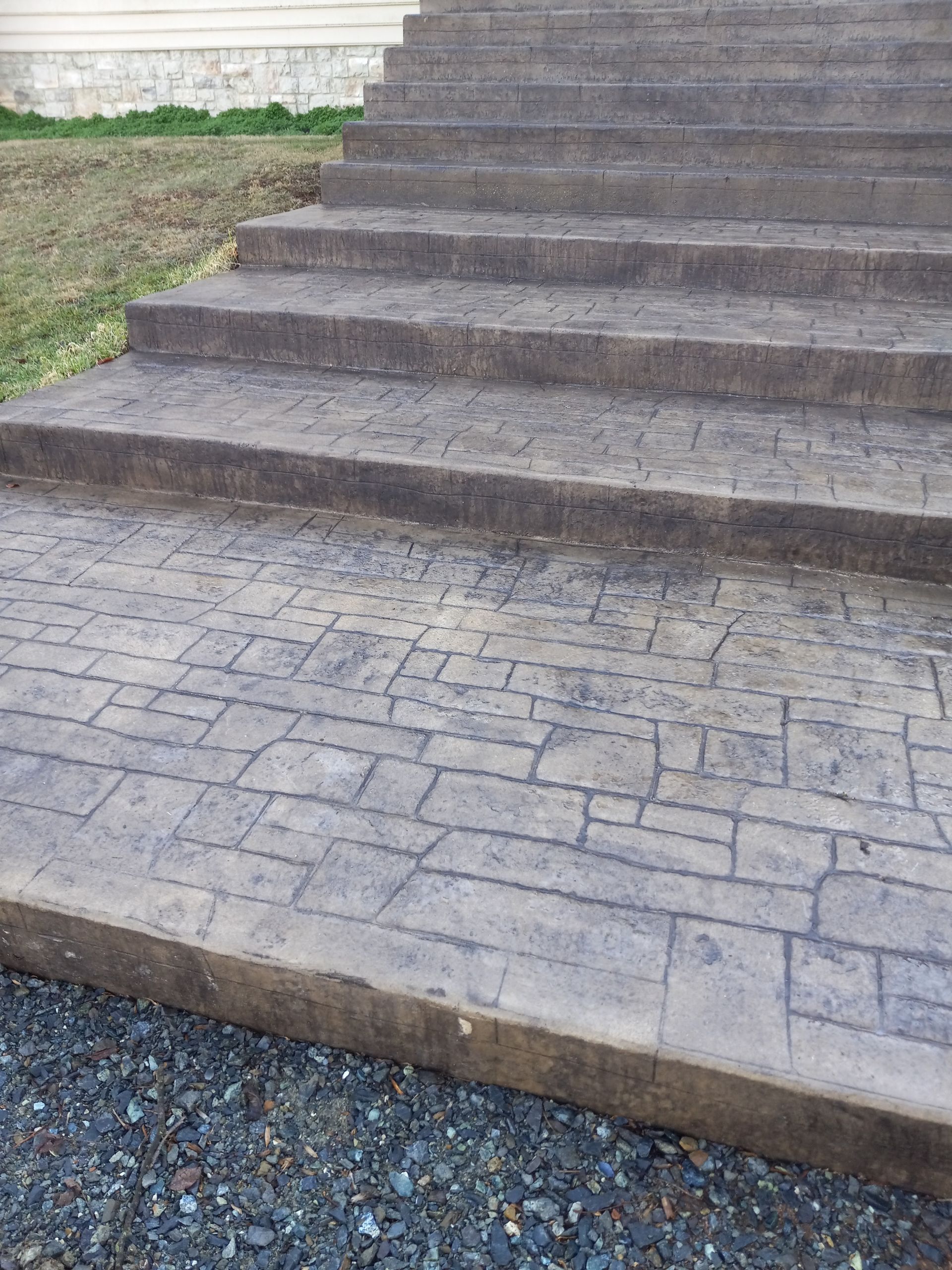Stone steps leading to a paved walkway and gravel, viewed from below