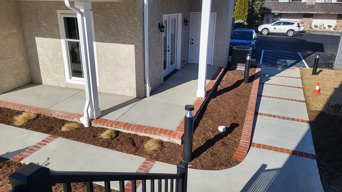 Front porch with white columns, paver walkway, red mulch, and a blue truck parked near the driveway.