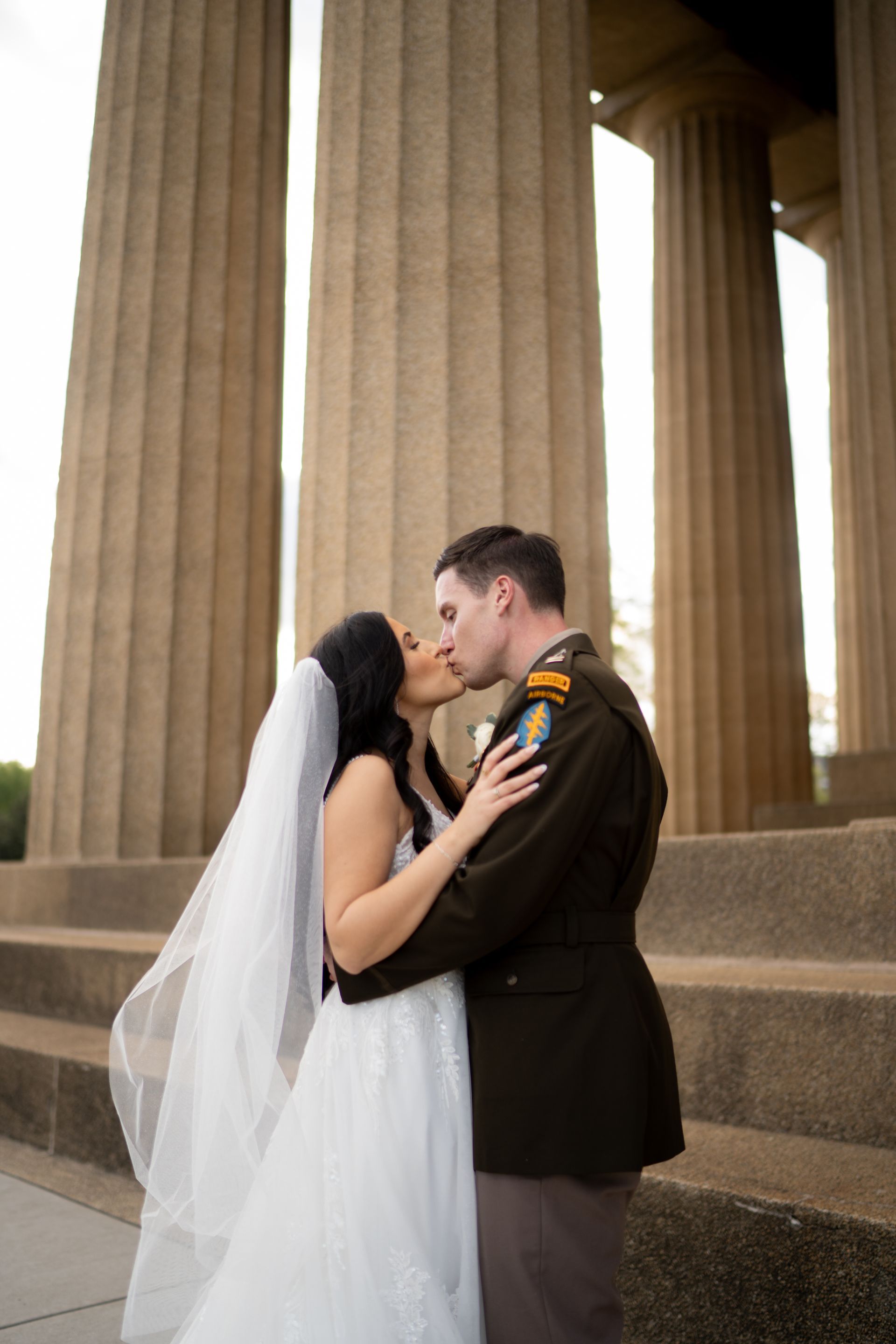 Bride and groom kissing in front of the Parthenon in Nashville after their wedding ceremony