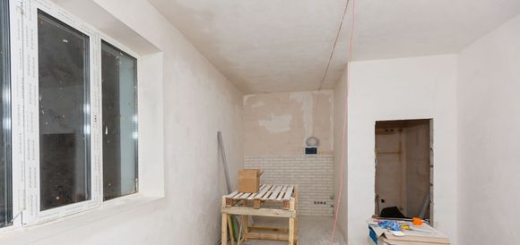 a room that is being remodeled with two windows and a wooden table .