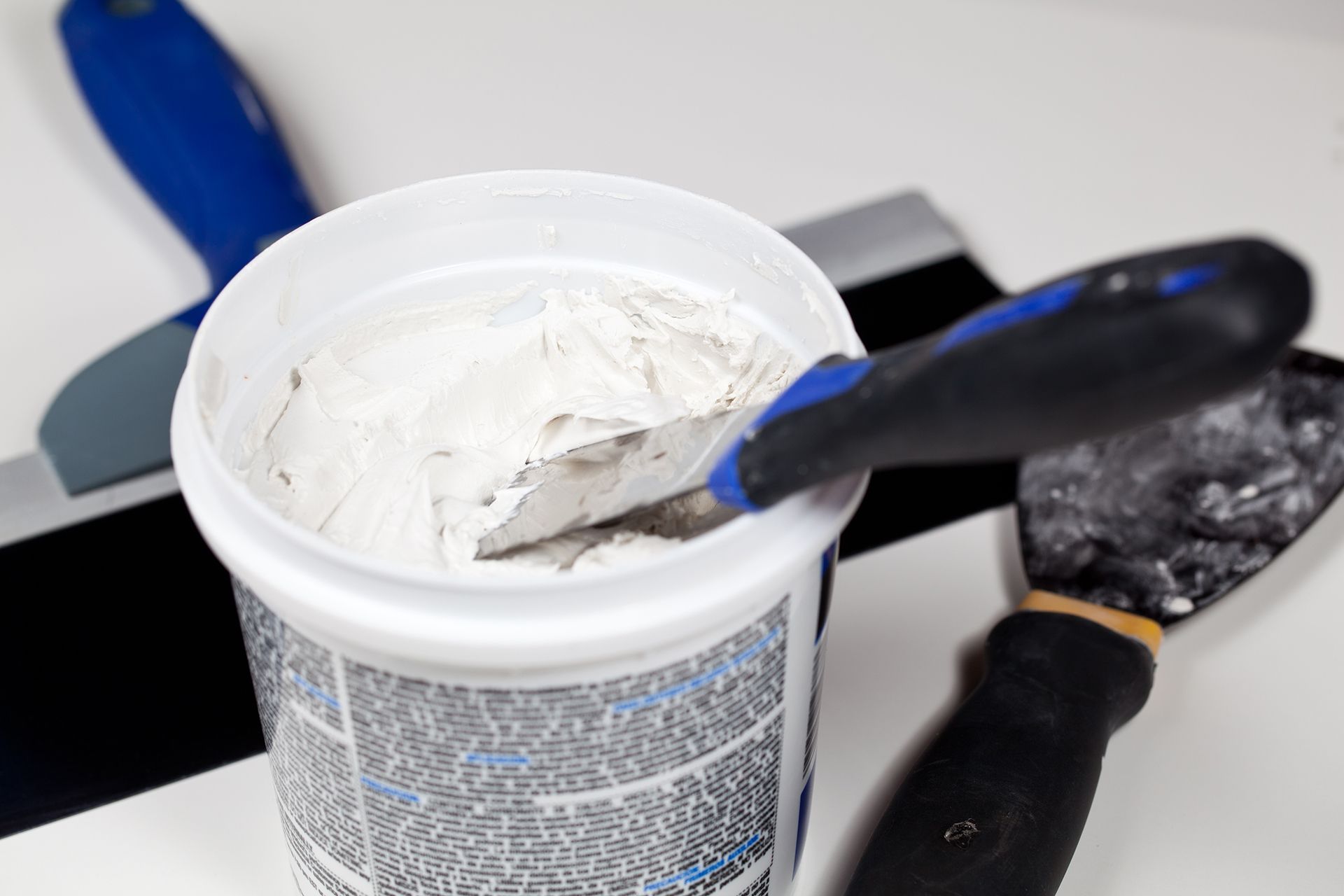 a bucket of white paint with a spatula in it