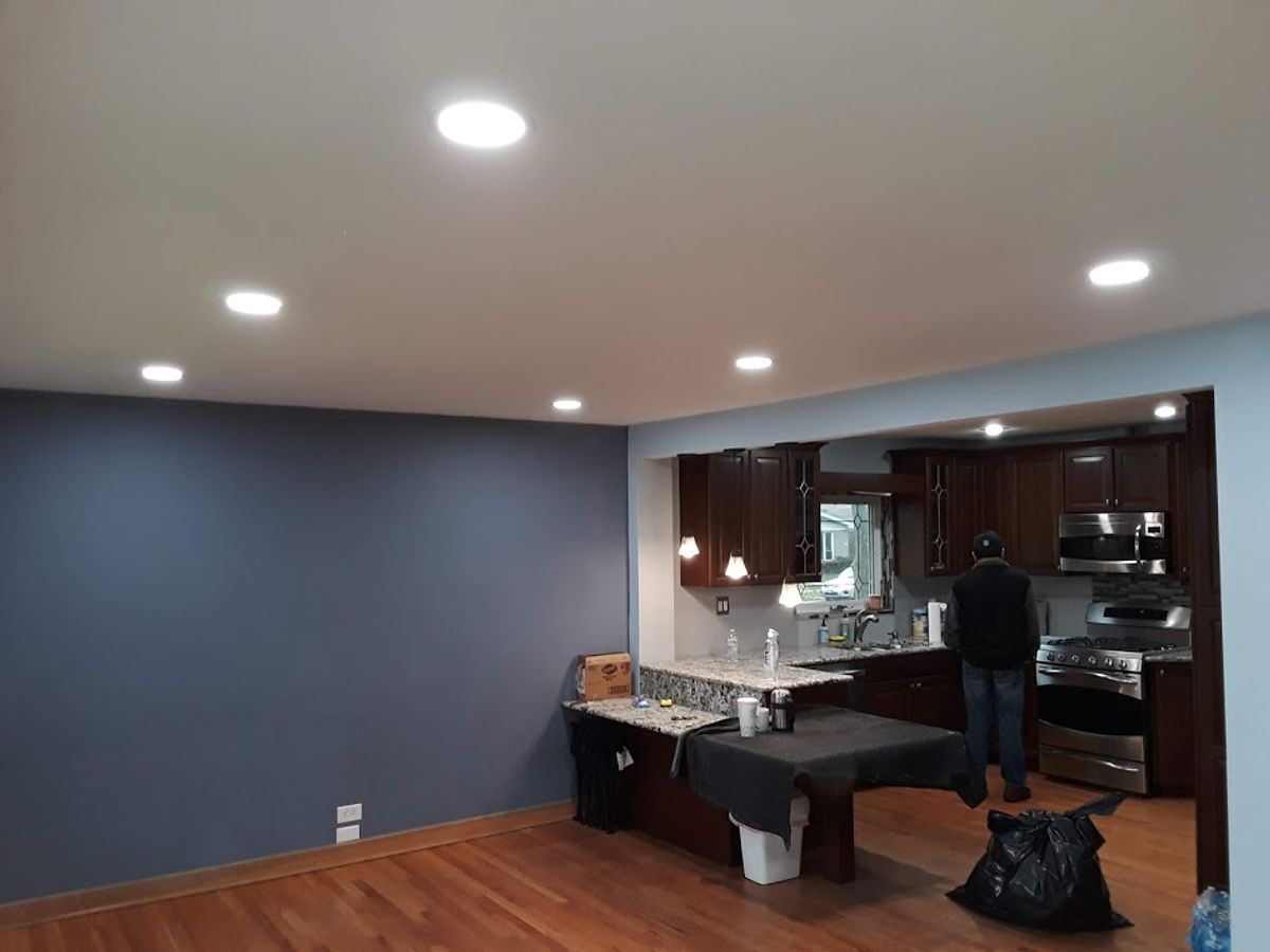 A man is standing in a living room next to a kitchen.