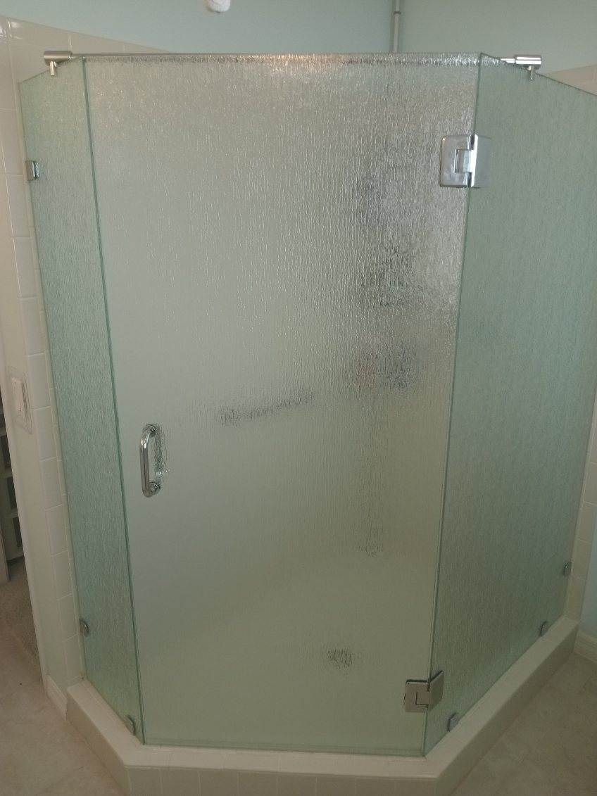 Textured glass shower enclosure with chrome hardware.