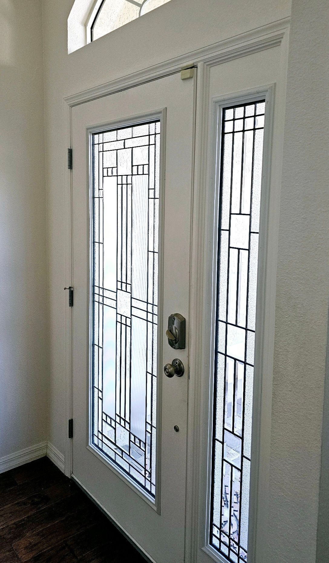 White front door with rectangular glass panes and sidelight, interior view.